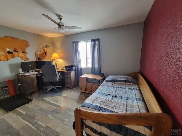 bedroom featuring a ceiling fan, a textured wall, and light wood finished floors