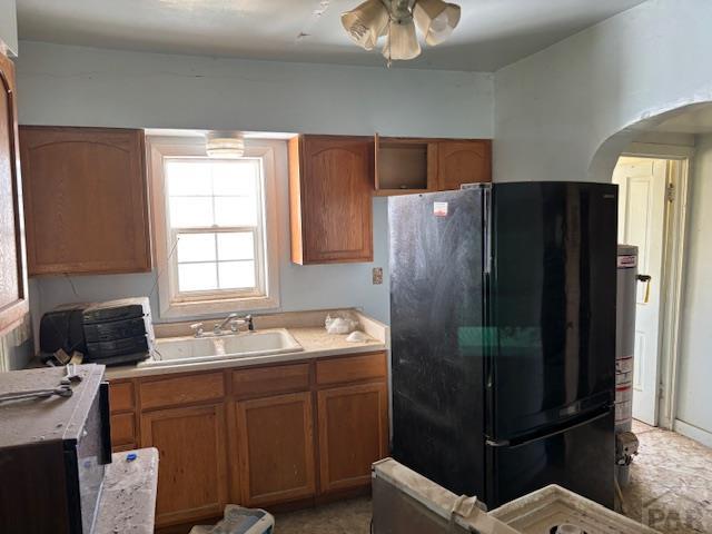 214 Short, Ordway, CO 81063 - kitchen featuring freestanding refrigerator, arched walkways, light countertops, brown cabinets, and a ceiling fan
