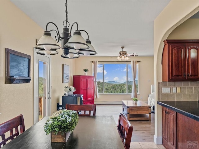 dining area with baseboard heating and ceiling fan with notable chandelier