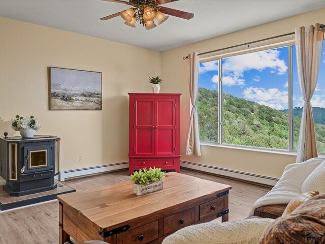 living area featuring baseboard heating, light wood-style flooring, and a wood stove