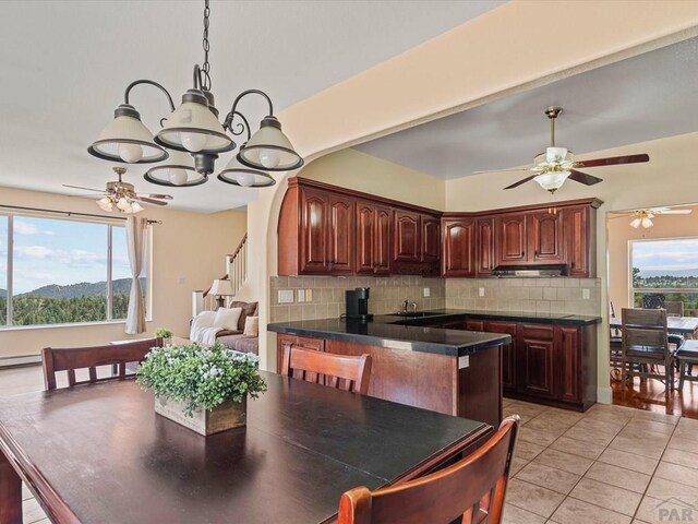 kitchen with a sink, dark countertops, tasteful backsplash, a peninsula, and light tile patterned floors