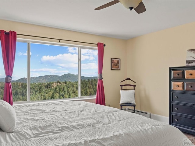 bedroom with a mountain view, a ceiling fan, baseboards, and a baseboard radiator