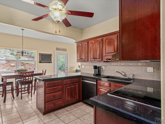 kitchen with dark countertops, dishwasher, decorative backsplash, a peninsula, and a sink