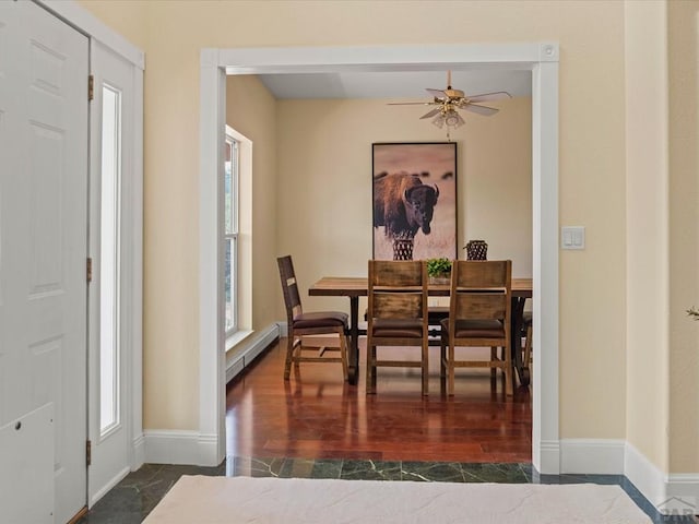 dining room featuring a baseboard heating unit, dark wood-type flooring, baseboards, and ceiling fan