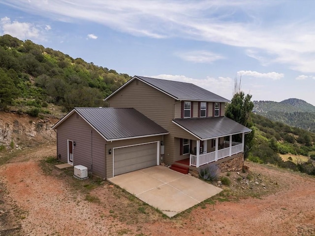 view of front of home with a porch, concrete driveway, an attached garage, and metal roof