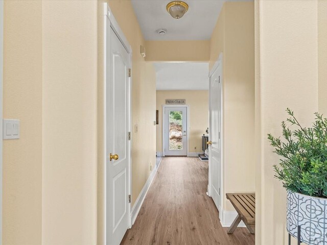 corridor with light wood-type flooring and baseboards