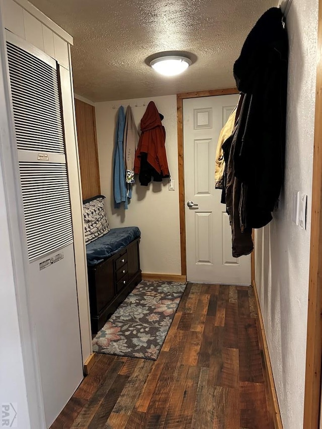 25433 County Rd 25, La Junta, CO 81050 - mudroom featuring a heating unit, dark wood-type flooring, a textured ceiling, and baseboards