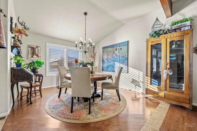 dining room with wood finished floors, an inviting chandelier, baseboards, and vaulted ceiling