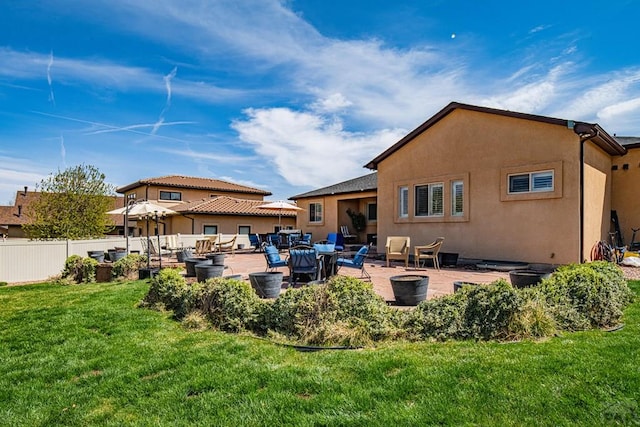 rear view of house featuring a patio area, stucco siding, fence, and a lawn