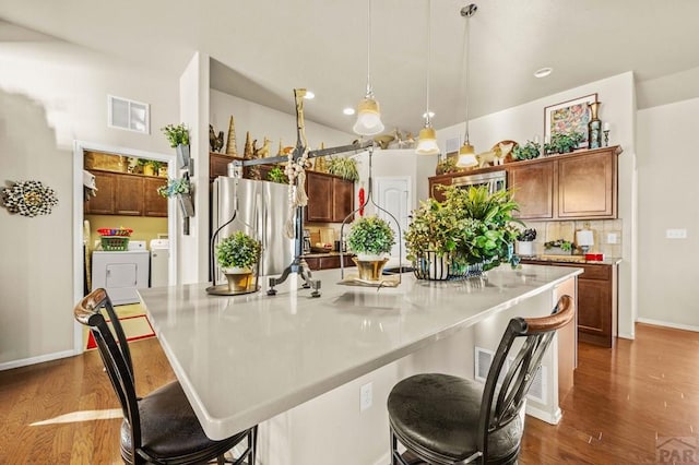 kitchen with decorative light fixtures, dark wood-style floors, washing machine and clothes dryer, and freestanding refrigerator