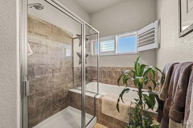 bathroom with a textured wall, a garden tub, and a stall shower