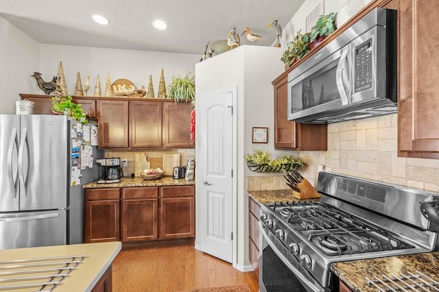 kitchen featuring stone counters, light wood-type flooring, recessed lighting, backsplash, and stainless steel appliances