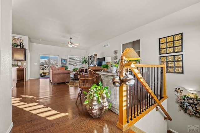 living area featuring visible vents, baseboards, a ceiling fan, and wood finished floors