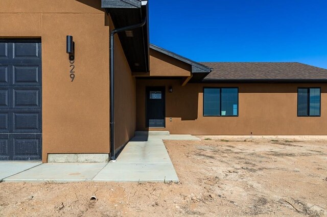 doorway to property with a garage and stucco siding