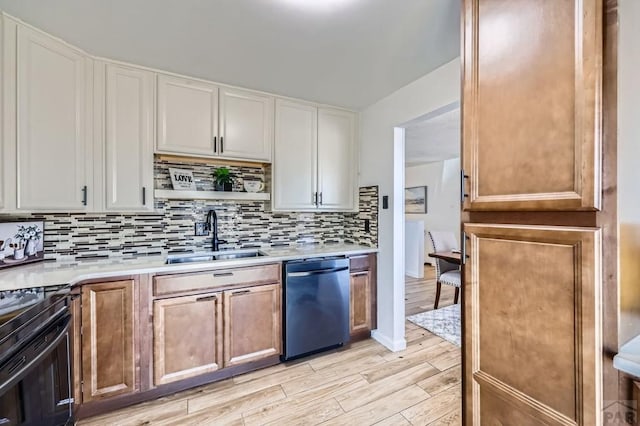 kitchen featuring stainless steel dishwasher, white cabinetry, light countertops, and a sink