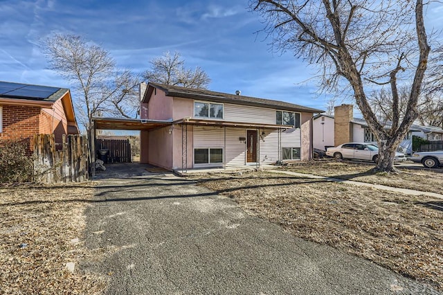 view of front facade featuring an attached carport, driveway, and fence