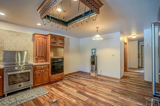 5207 N Creek Rd, Beulah, CO 81023 - kitchen featuring stainless steel gas range, black oven, wood finished floors, brown cabinets, and tasteful backsplash