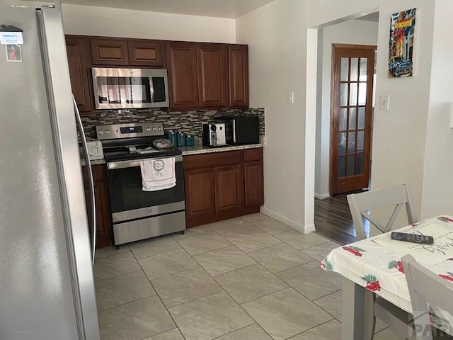 kitchen with baseboards, stainless steel appliances, light countertops, and decorative backsplash
