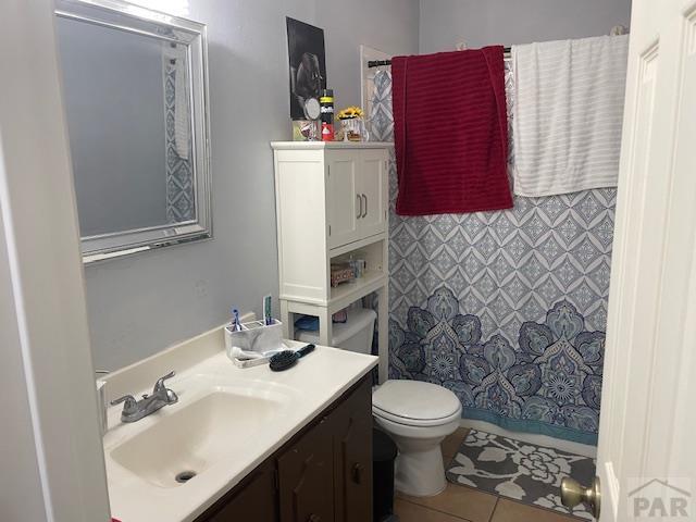 bathroom with toilet, vanity, curtained shower, and tile patterned floors