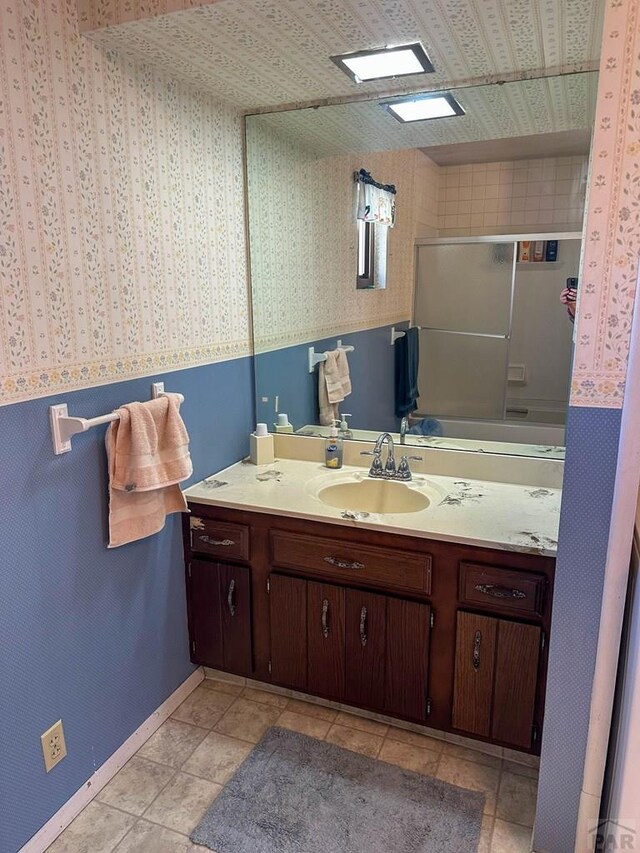 bathroom featuring wallpapered walls, vanity, baseboards, and tile patterned floors