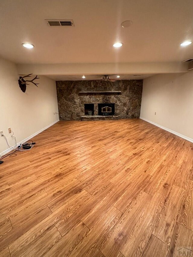 unfurnished living room with visible vents, baseboards, light wood-style flooring, a stone fireplace, and recessed lighting