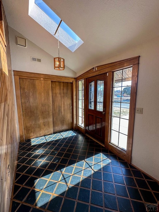 foyer entrance featuring vaulted ceiling with skylight and visible vents