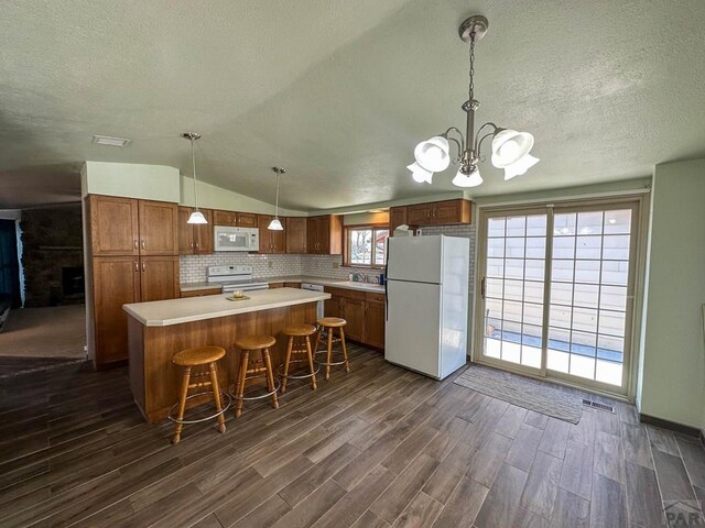 kitchen with hanging light fixtures, white appliances, light countertops, and a center island