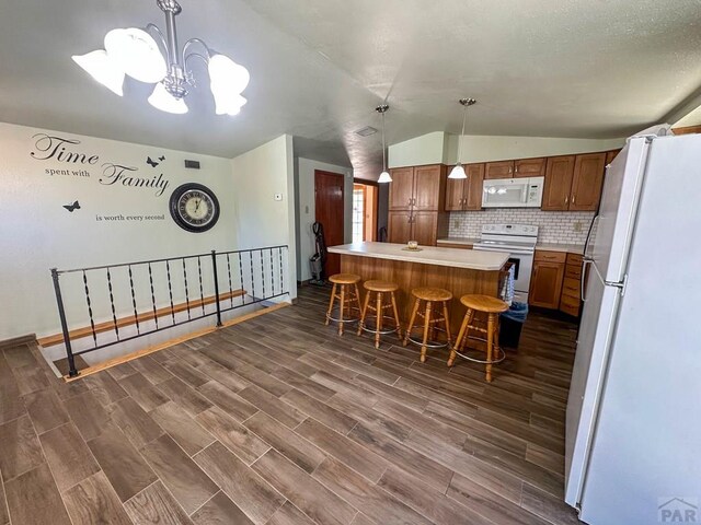 kitchen featuring pendant lighting, white appliances, light countertops, and brown cabinetry