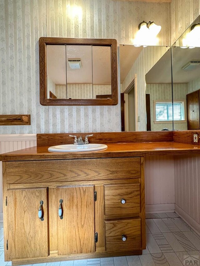 bathroom with vanity and wallpapered walls