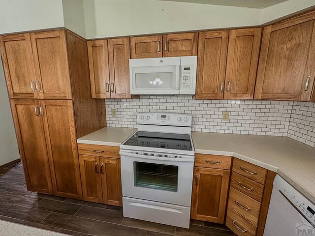 kitchen featuring brown cabinets, white appliances, light countertops, and backsplash