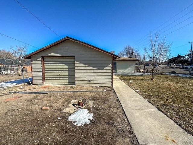 view of home's exterior with dirt driveway, an outbuilding, fence, and a garage