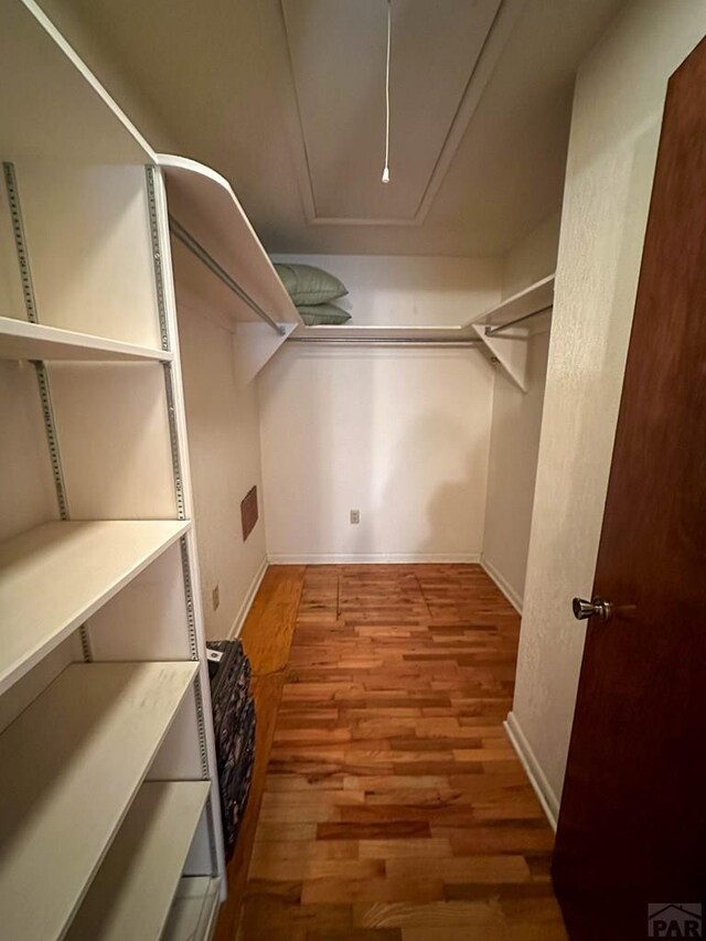 spacious closet with attic access and wood finished floors