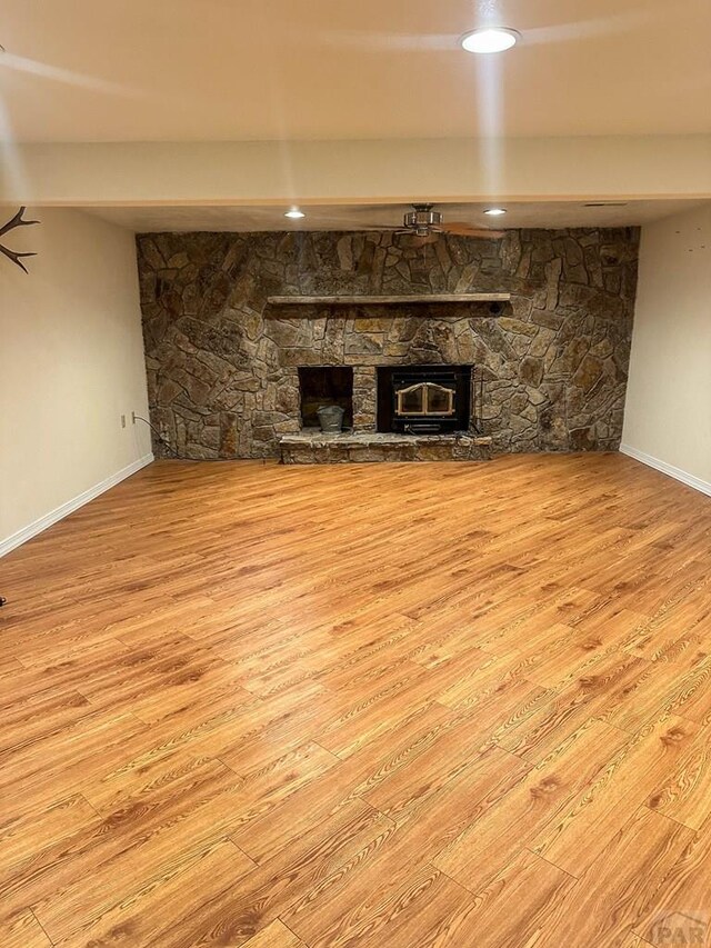 unfurnished living room featuring light wood finished floors, a fireplace, baseboards, and recessed lighting