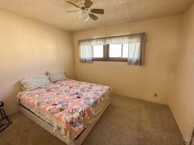 bedroom with a ceiling fan, carpet flooring, and a textured ceiling