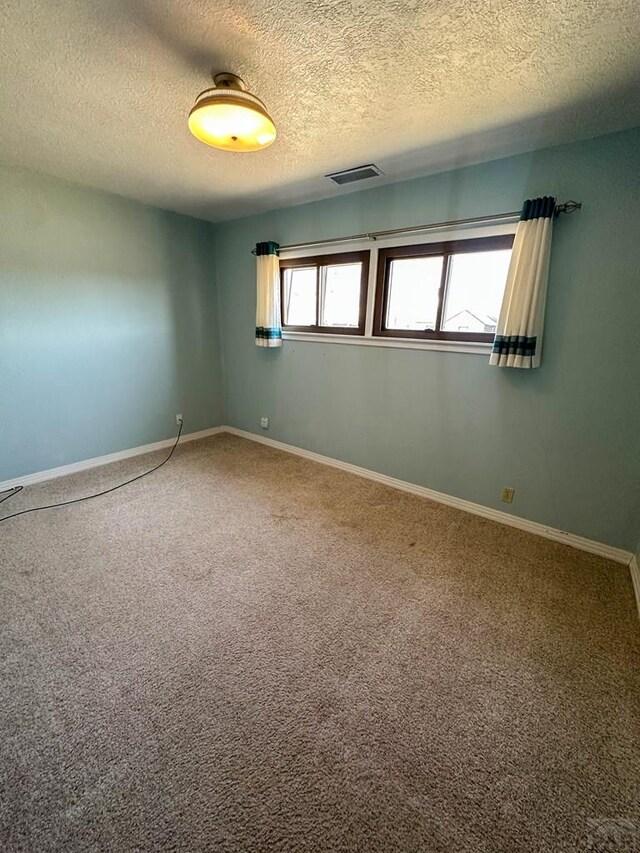 empty room featuring baseboards, visible vents, and carpet flooring