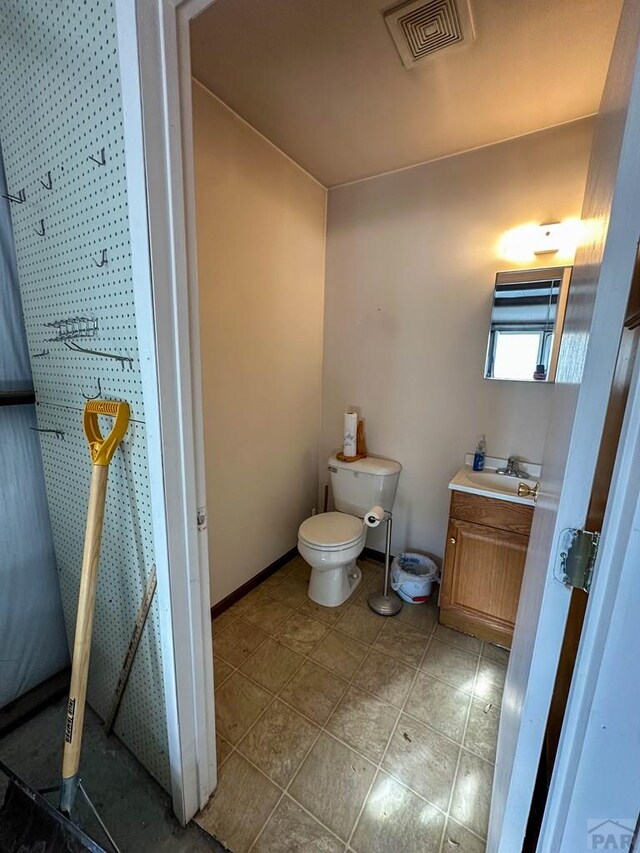 bathroom featuring toilet, vanity, visible vents, baseboards, and tile patterned floors