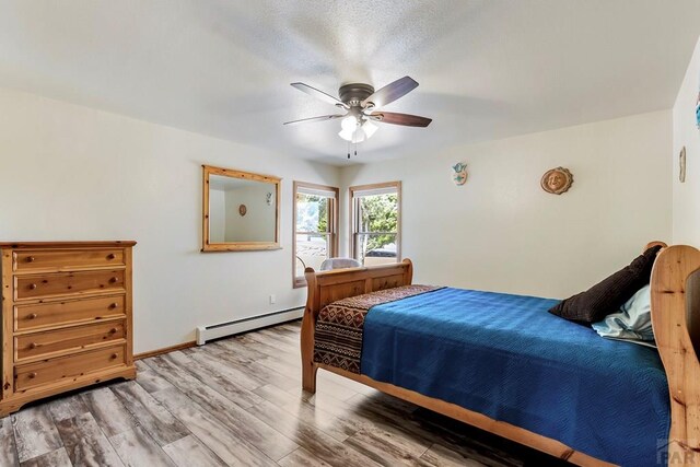 bedroom featuring a ceiling fan, a baseboard radiator, baseboards, and wood finished floors