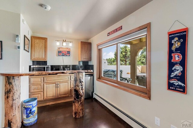 kitchen with finished concrete floors, appliances with stainless steel finishes, baseboard heating, and light countertops