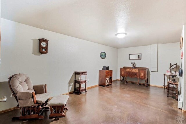 sitting room featuring finished concrete flooring and baseboards