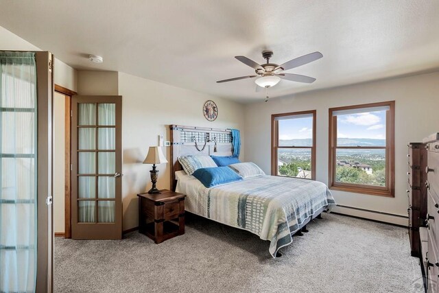 bedroom featuring a baseboard heating unit, a ceiling fan, and light colored carpet