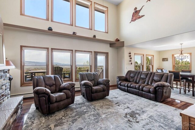 living area with dark wood-type flooring, a fireplace, a baseboard heating unit, a mountain view, and a notable chandelier