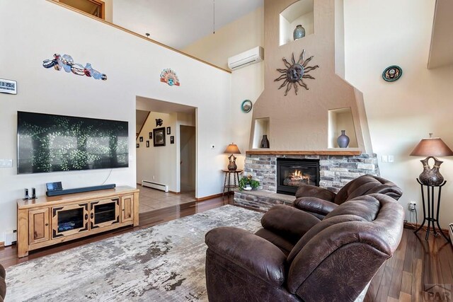 living area featuring an AC wall unit, a baseboard radiator, light wood-style flooring, and a brick fireplace