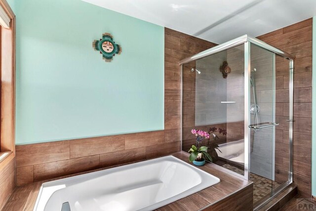 bathroom featuring a stall shower and a bath