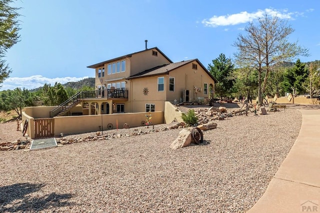 rear view of house with stairs and stucco siding