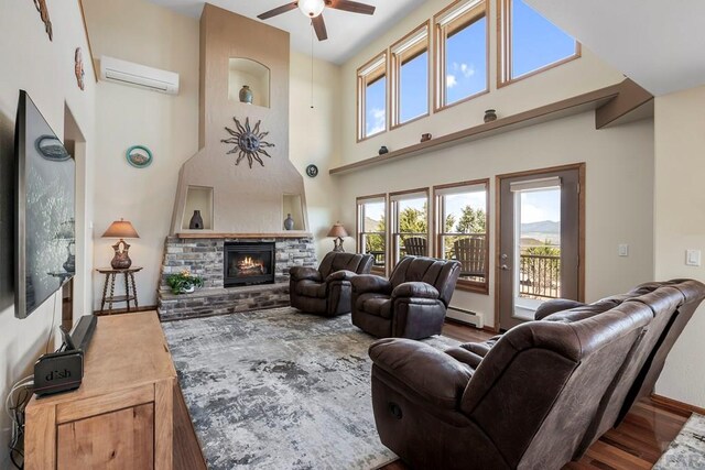 living room with wood finished floors, a wall unit AC, plenty of natural light, and a glass covered fireplace