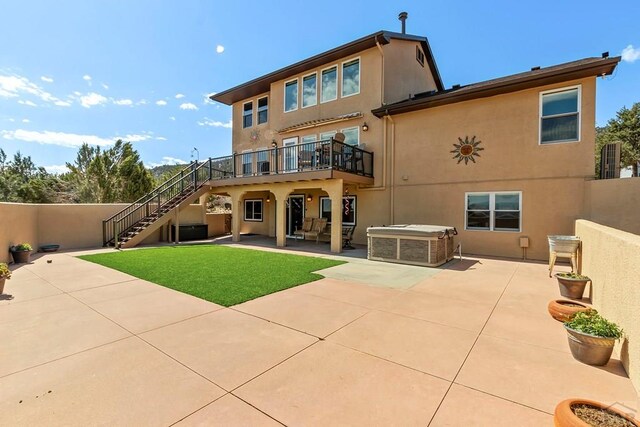 back of property featuring a patio area, a yard, stairway, and stucco siding