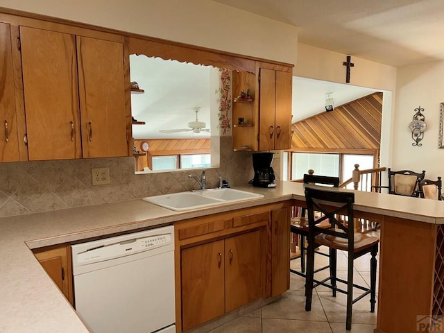 kitchen featuring light tile patterned floors, a sink, light countertops, backsplash, and dishwasher