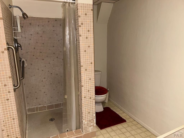 bathroom featuring a stall shower, tile patterned flooring, baseboards, and toilet