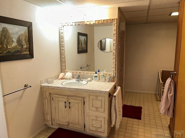 bathroom featuring a drop ceiling, vanity, and baseboards