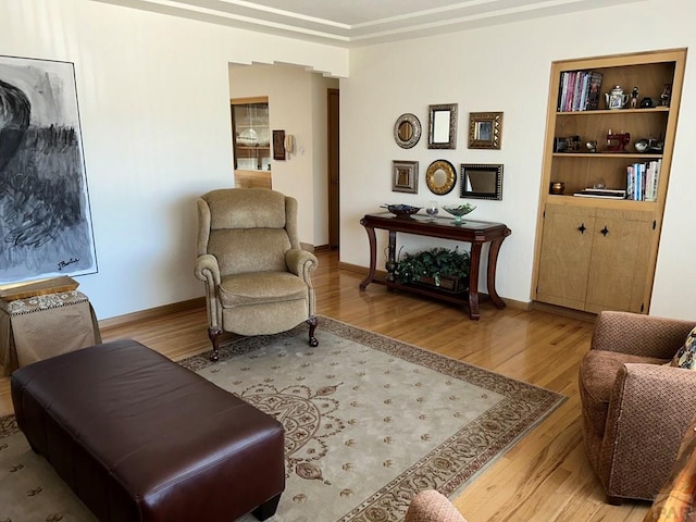 sitting room featuring light wood-style floors, baseboards, and built in features